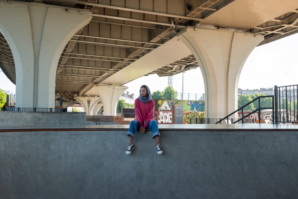 Woman sitting under bridge